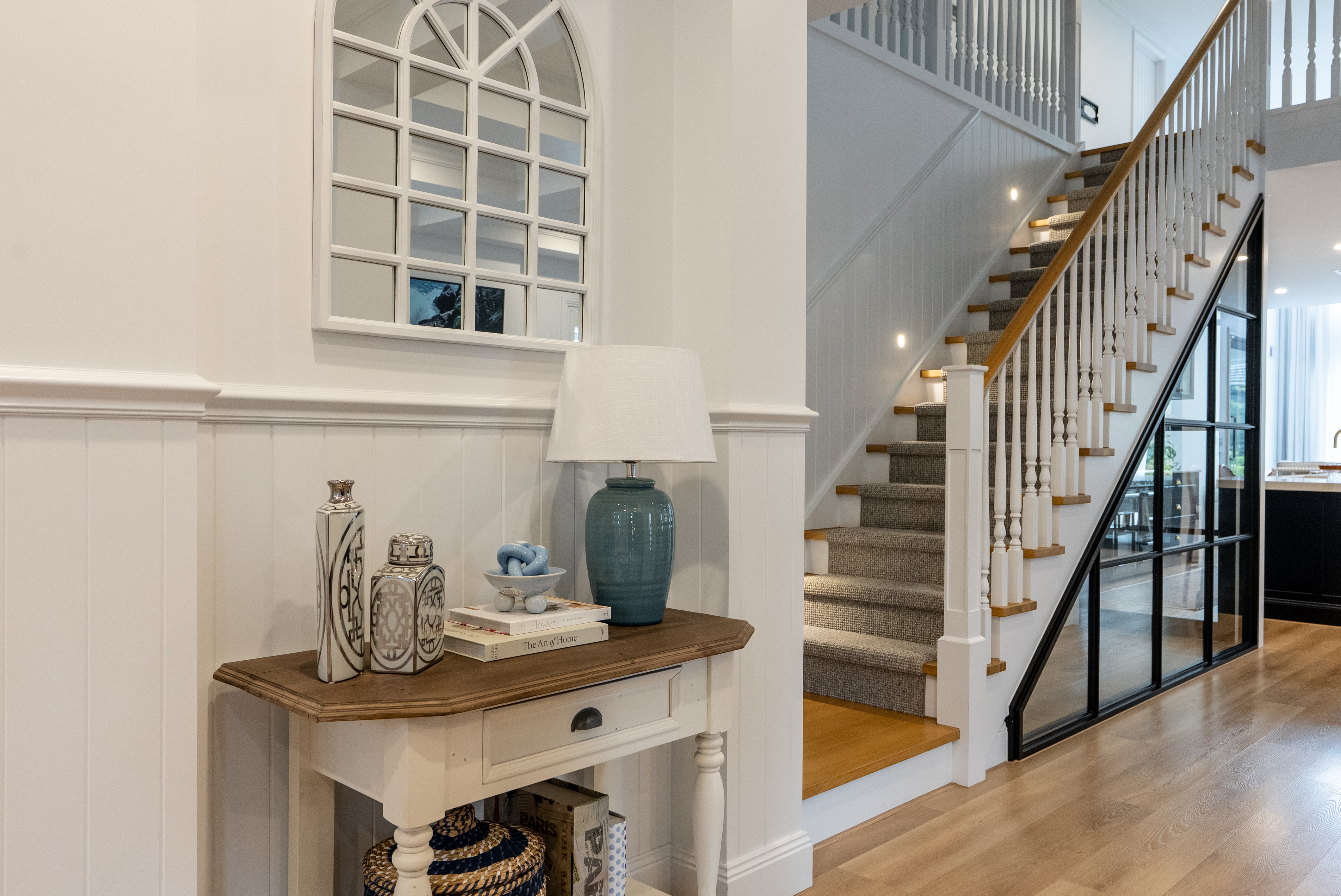 Refined Hamptons foyer with wainscot panelling and timber staircase