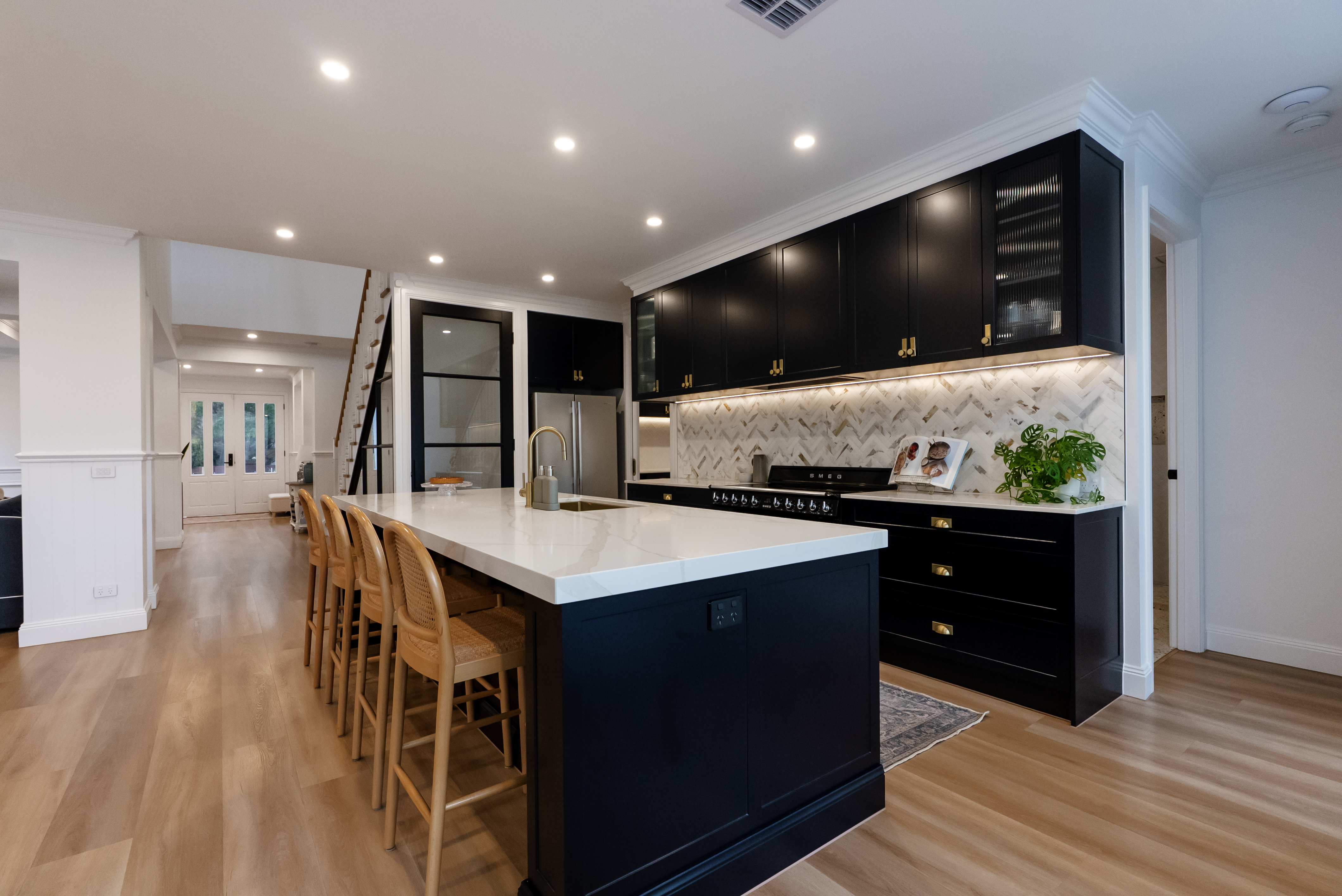Refined navy kitchen with marble herringbone splashback and brass fittings
